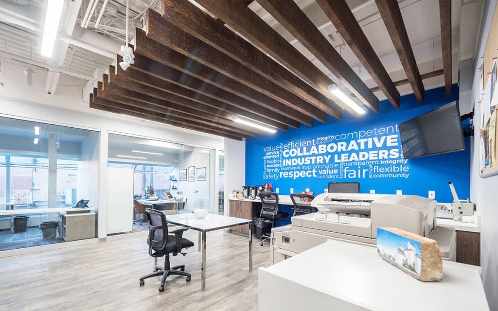 Open-ceiling office with a painted black ceiling and blue feature wall
